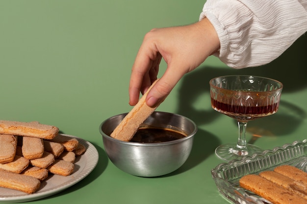 Hand, die den Ladyfinger in die Kaffeetasse steckt