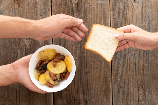 Kostenloses Foto hand, die der bedürftigen person eine schüssel mit essen und brot gibt