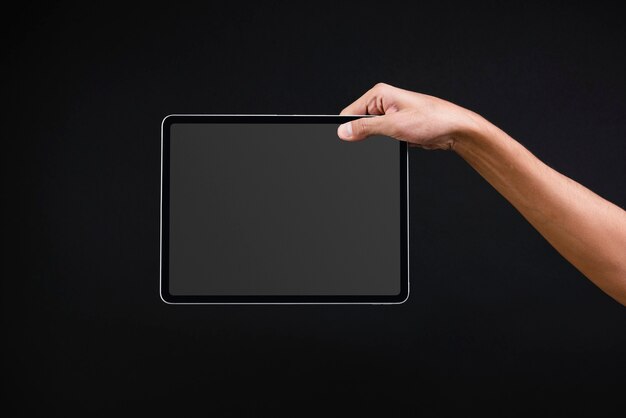 Hand, die digitales Tablett mit leerem schwarzen Bildschirm hält