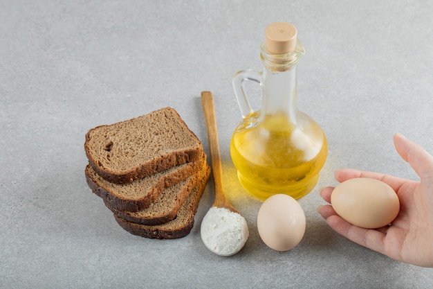 Hand, die eine Glasflasche Öl mit Brotscheiben öffnet.