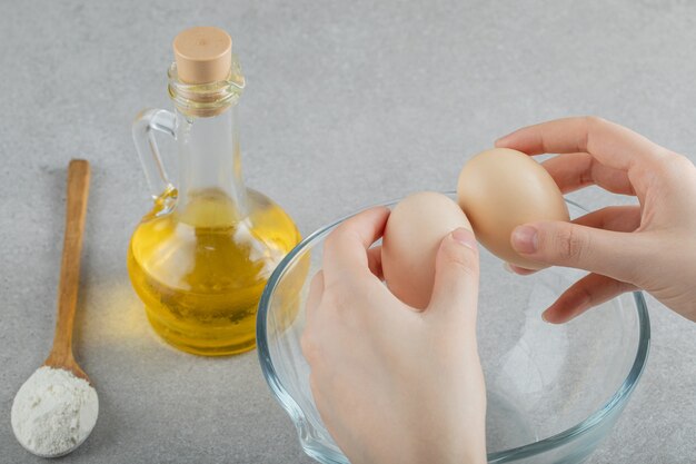 Hand, die eine Glasflasche Öl mit Brotscheiben öffnet.