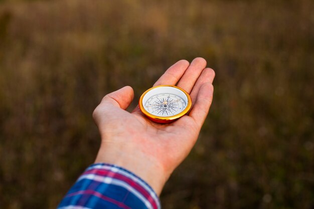 Hand, die einen Kompass mit unscharfem Hintergrund zeigt