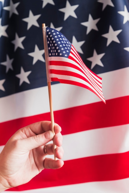 Hand, die Fahnenmast mit amerikanischer Flagge hält