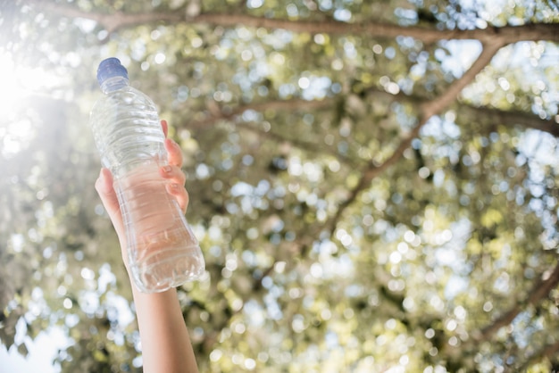 Hand, die Flasche Wasser hält