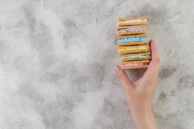 Kostenloses Foto hand, die geschmackvolle plätzchen auf grauem hintergrund hält