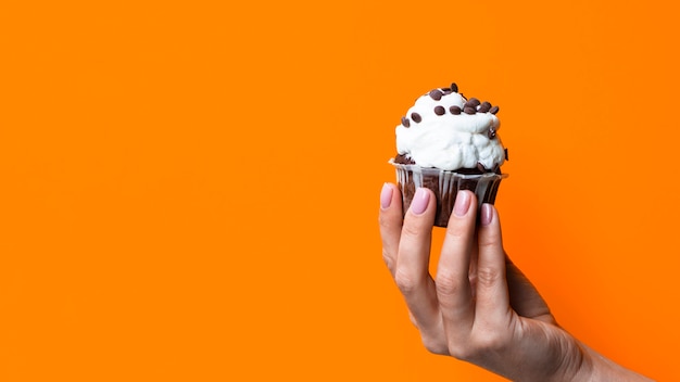 Hand, die geschmackvolles Muffin mit Kopienraum hält