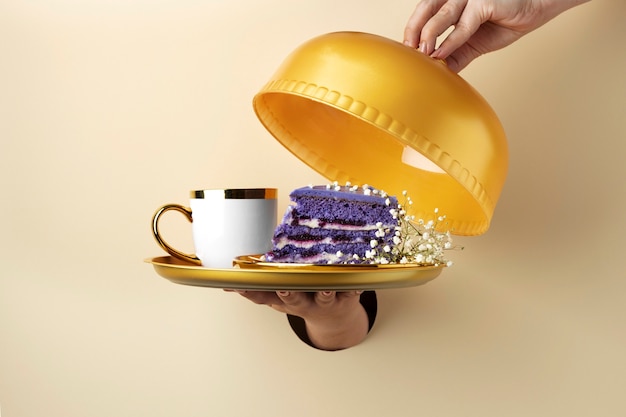 Hand, die goldenen Teller mit Kuchen hält