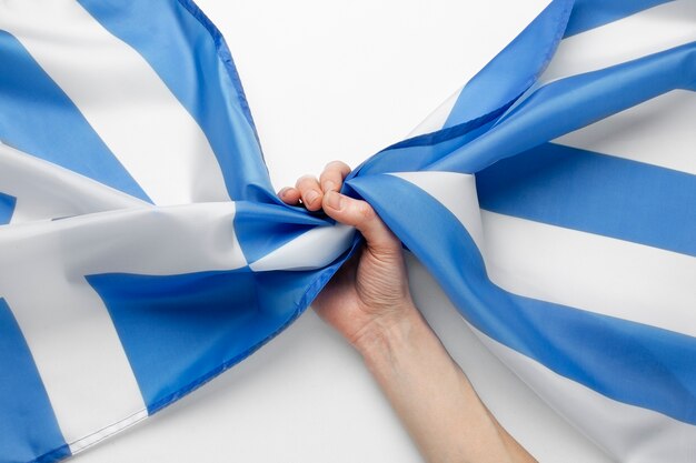 Hand, die griechischen Flaggenstoff hält