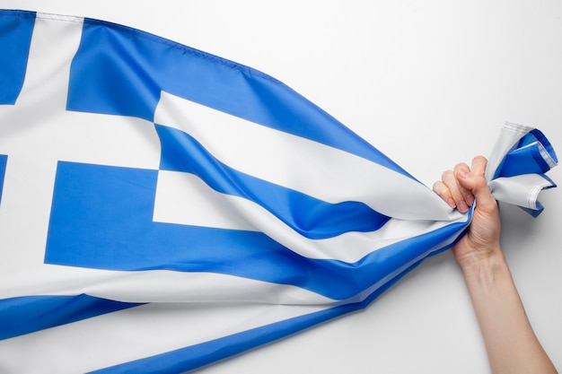 Hand, die griechischen Flaggenstoff hält