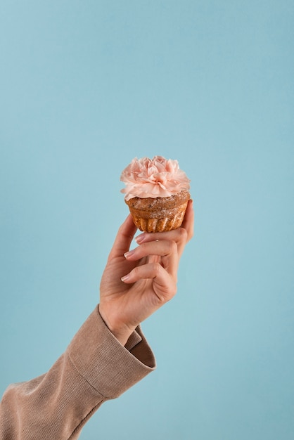 Hand, die Öko-Cupcake mit Blume hält