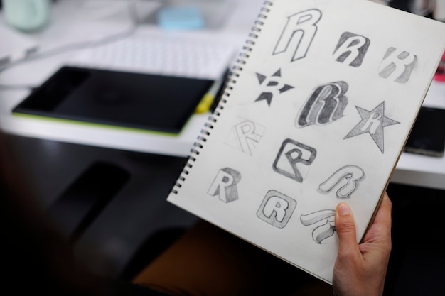 Hand, die notizbuch mit drew brand logo creative design-ideen hält