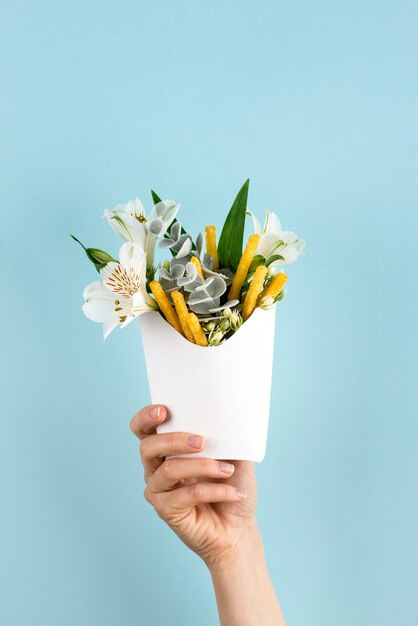 Hand, die Pommes mit blauem Hintergrund hält