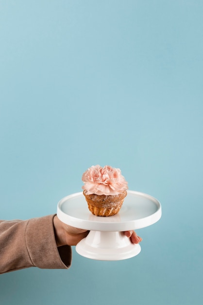 Kostenloses Foto hand, die servierplatte mit kleinem kuchen hält