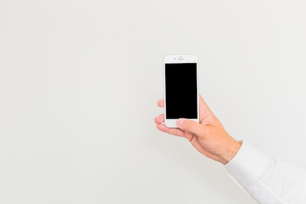 Kostenloses Foto hand, die smartphone gegen weißen hintergrund hält