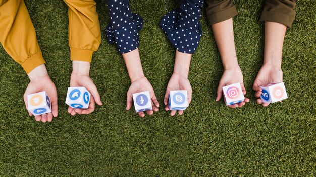 Hand, die Social Media-APP-Ikonenblöcke auf grünem Gras hält