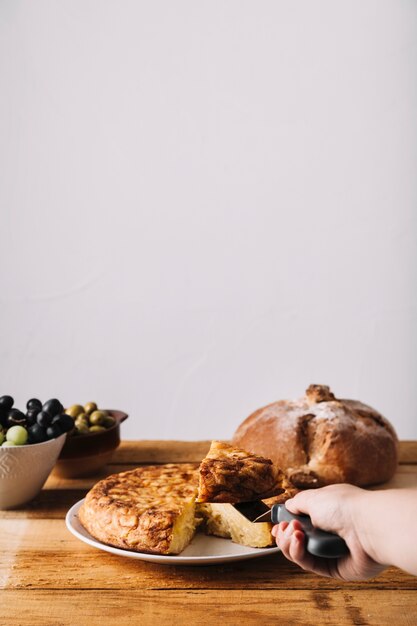 Hand, die Stück Kuchen nahe Lebensmittel nimmt