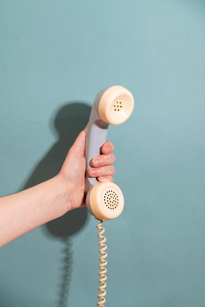 Hand, die Telefon mit blauem Hintergrund hält