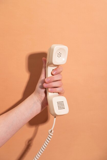 Hand, die Telefon mit orangefarbenem Hintergrund hält