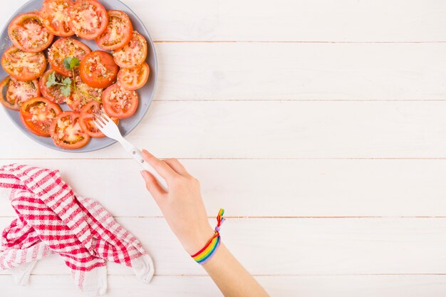 Hand, die Tomate von der Platte sticht