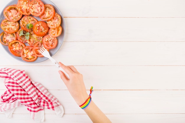 Hand, die Tomate von der Platte sticht