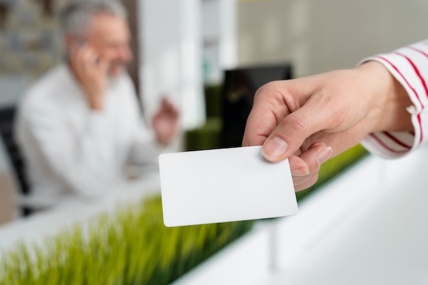 Hand, die Visitenkarte im Büro hält