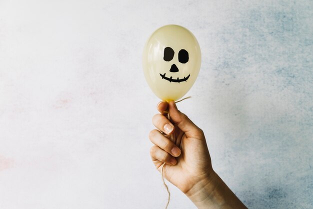 Hand, die weißen Ballon mit furchtsamem Gesicht hält