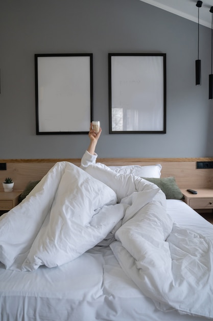 Hand, die zu Hause einen Tasse Kaffee im Bett hält