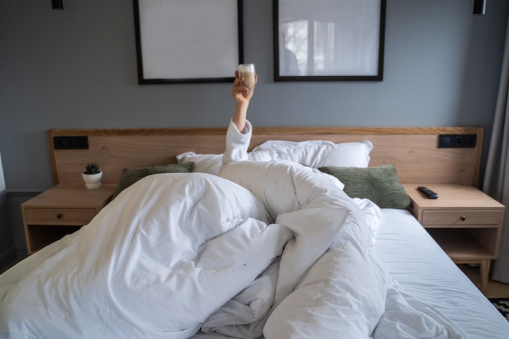 Kostenlose Foto hand, die zu hause im bett eine tasse kaffee hält