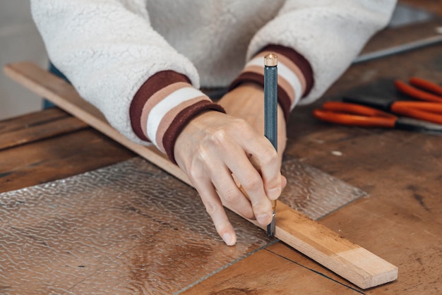 Hand einer Glasmachermeisterin bei der Arbeit in einer Werkstatt