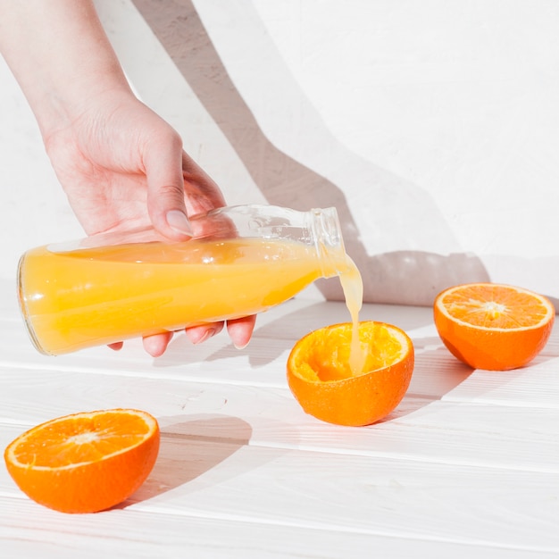 Hand gießt Saft in gepresster Orange