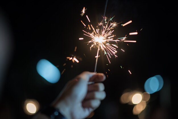 Hand hält ein brennendes Wunderkerzenlicht