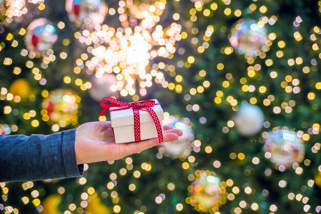 Hand hält ein Geschenk auf einem glänzenden Hintergrund