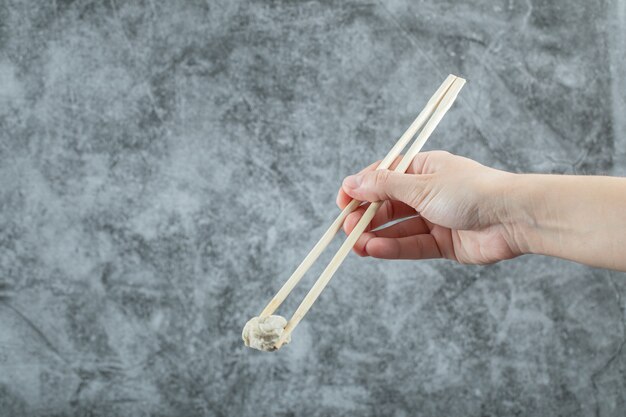 Hand hält ein Stäbchen mit Knödel