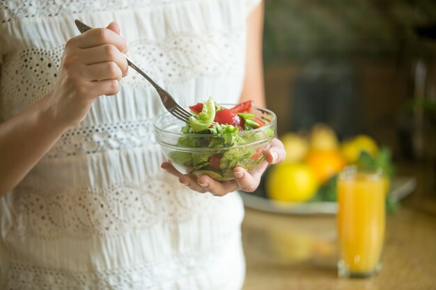 Hand hält eine Schüssel mit Salat, Gabel in einem anderen