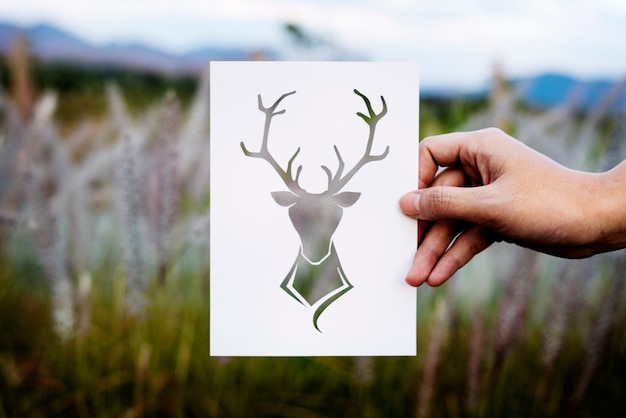 Kostenloses Foto hand halten deer mit dem geweih-papier, das mit natur schnitzt