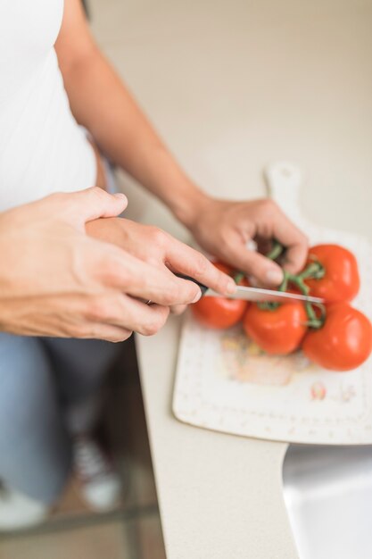 Hand helfende Frau der Schnitthand, die Gemüse schneidet