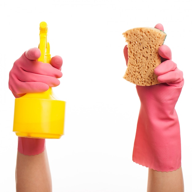 Hand in einem rosa Handschuh, der Spray und Schwamm hält