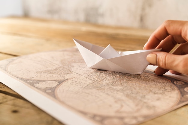 Kostenloses Foto hand legt papierboot auf karte