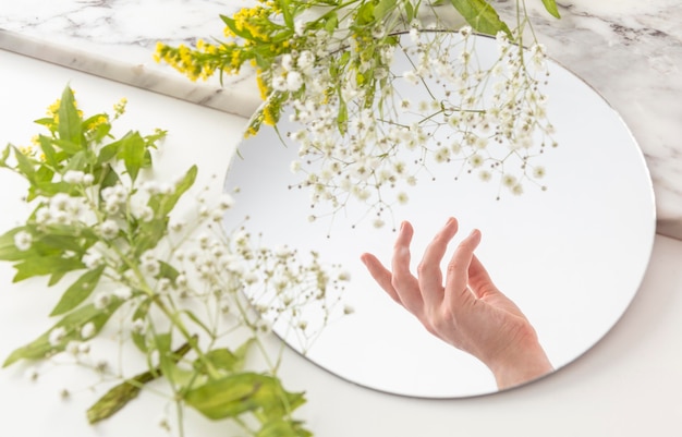 Kostenloses Foto hand mit blumen im spiegel