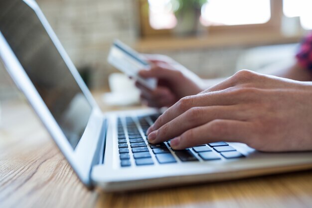 Hand mit einem Laptop eine Online-Zahlung in Coffee-Shop zu machen