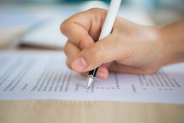 Hand mit einem Stift schriftlich auf einem Papier