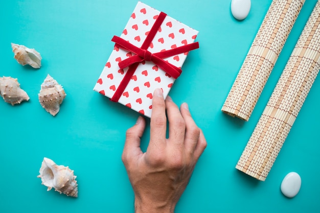 Hand mit Geschenkbox und dekorativen Elementen