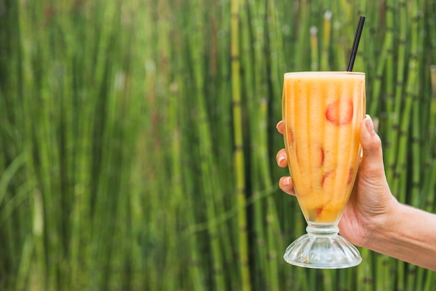 Hand mit Glas Smoothie in der Nähe von Bambus