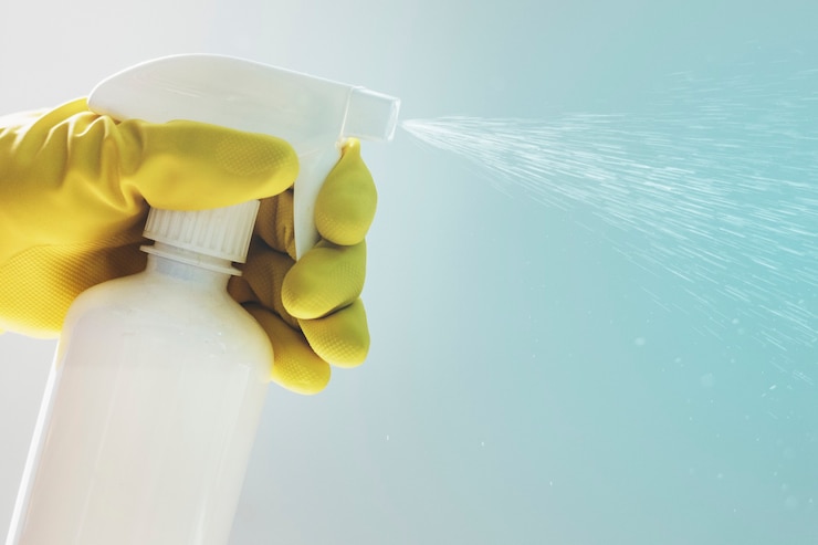 Kostenlose Foto hand mit gummihandschuh, die eine weiße sprühflasche hält