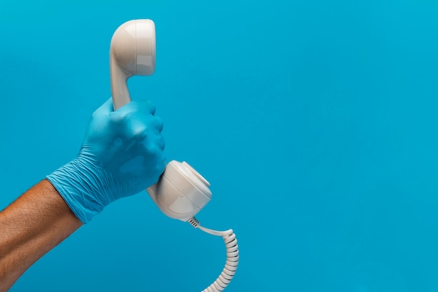 Hand mit Handschuh, der Telefonhörer mit Kopierraum hält