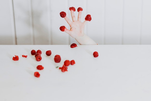 Hand mit Himbeeren an den Fingern