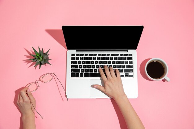 Hand mit Laptop auf rosa Oberfläche