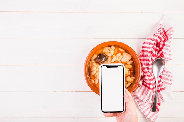 Kostenloses Foto hand mit mobile auf tisch mit essen platte