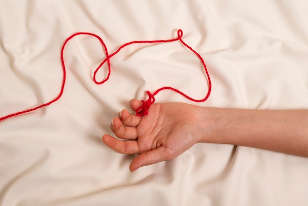 Hand mit rotem Faden