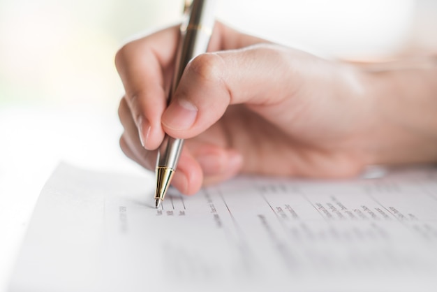 Hand mit Stift über Antragsformular.